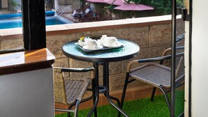 A small outdoor seating area with a round table and wicker chairs, overlooking a swimming pool and patio furniture. - Delight Homes by Della (Nairobi)