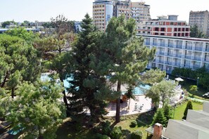 Un hotel con piscina rodeada de árboles, un patio interior y edificios modernos al fondo.