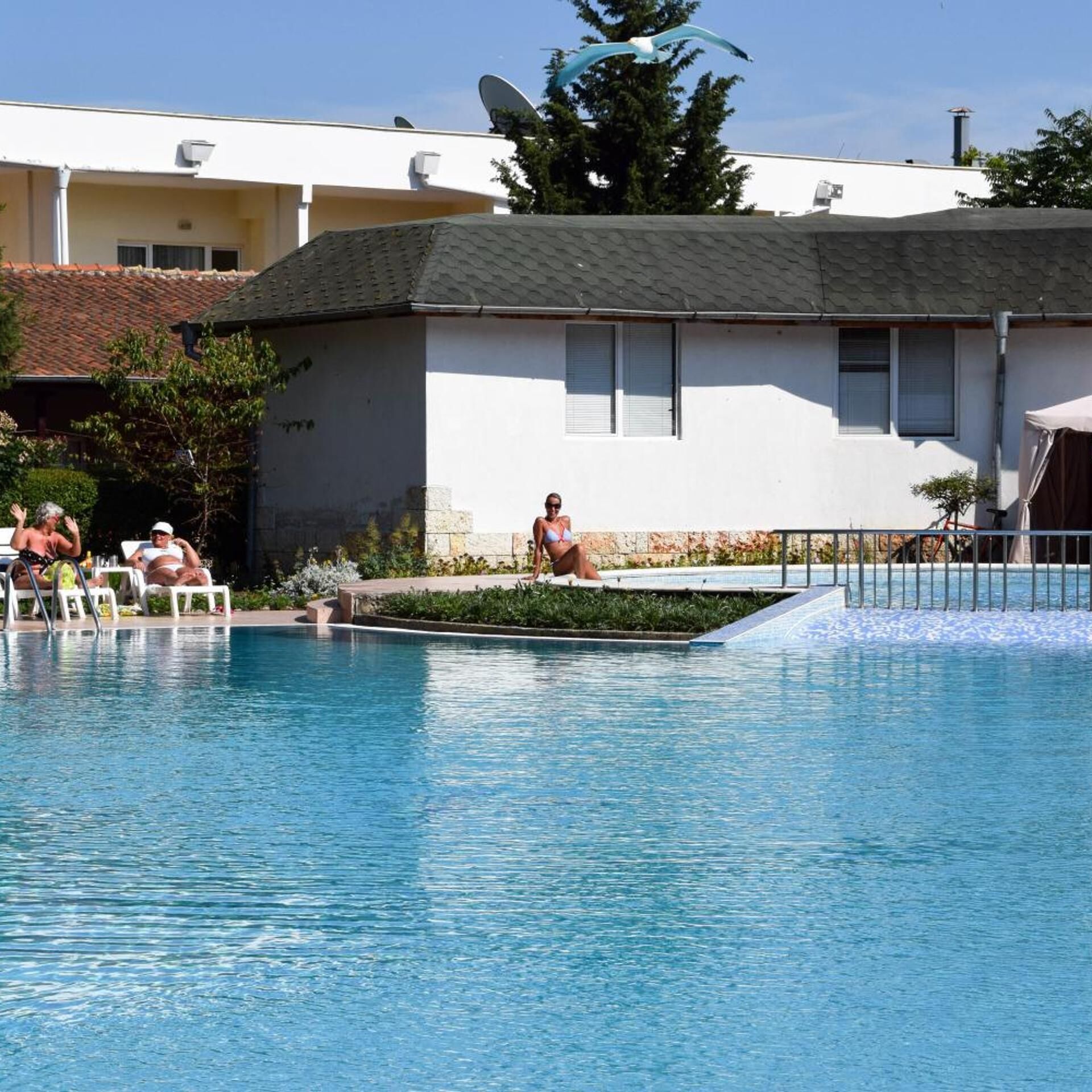 A swimming pool with lounge chairs and a building in the background.