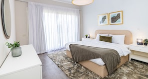 A hotel room with a bed, bedside table, lamp, and a large window with curtains. - Prime Select The Crown (6th of October City)