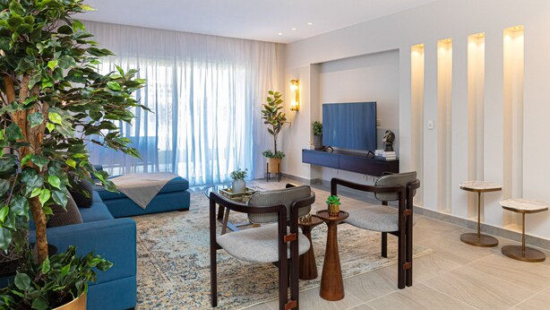 Una sala de estar moderna con sofá, sillones, una mesa de centro y televisor.