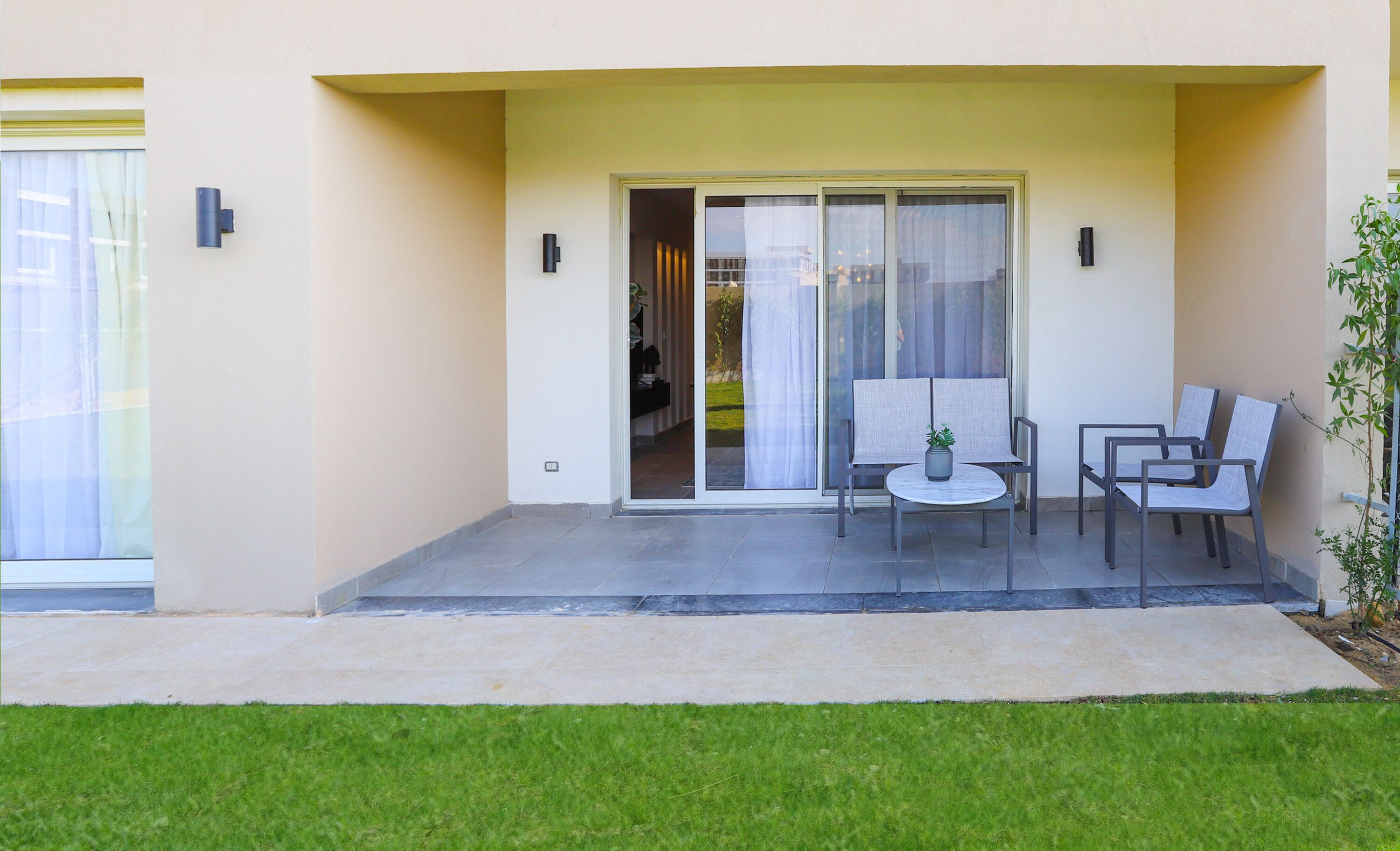 A patio with a table and chairs, a sliding glass door, and a small potted plant.