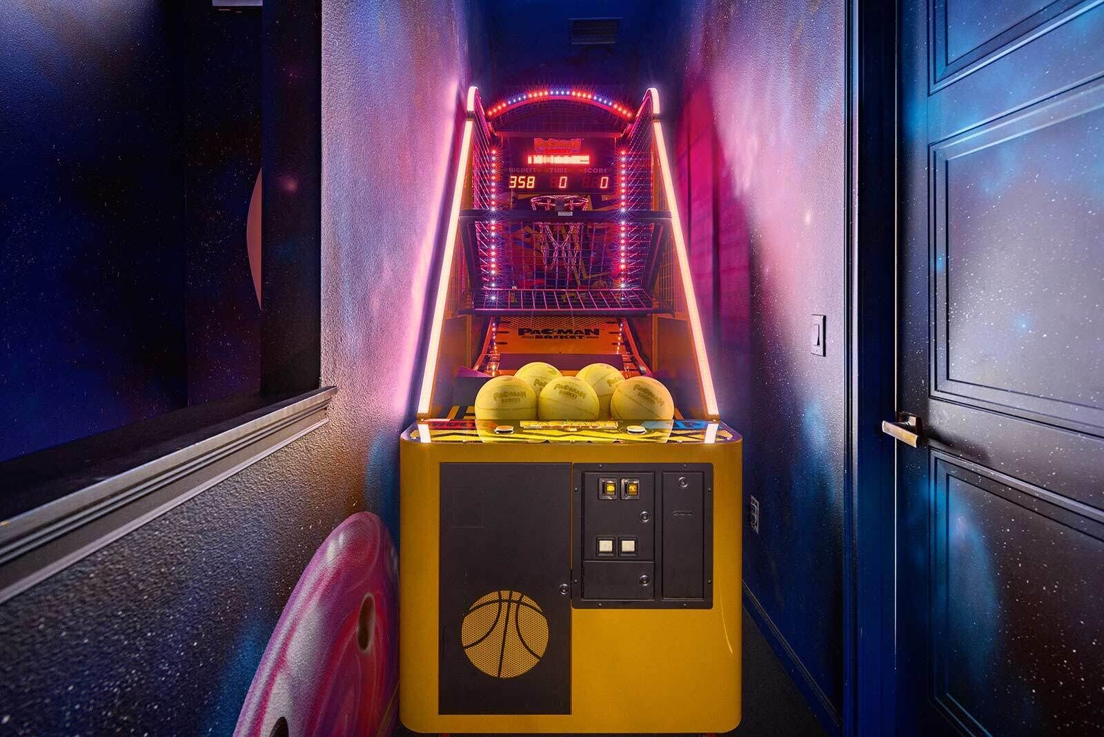 Eine Basketball-Spielmaschine mit Neonlichtern und Punktestand in einem Flur.
