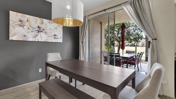 Un espace repas moderne avec une table en bois foncé, un banc et un grand tableau abstrait accroché au mur.