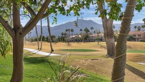 Un parcours de golf avec un tracé bien défini, des palmiers et une montagne en arrière-plan.