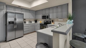 Une cuisine moderne avec des meubles gris, des appareils en acier inoxydable et un îlot central.