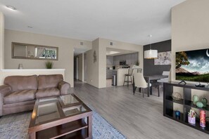 Un salon moderne avec un canapé en cuir, une table basse en verre et un téléviseur à écran plat posé sur un meuble.