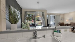 Une salle de bain moderne avec un grand lavabo, une plante en pot et une vue sur l’espace extérieur.