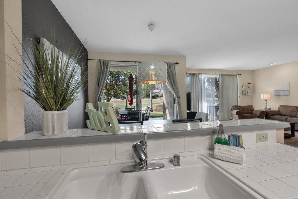 A modern bathroom with a large sink, a mirror, and a potted plant.