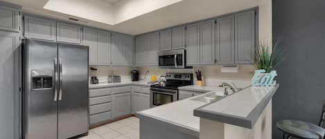 Una cocina moderna con armarios grises, electrodomésticos de acero inoxidable, una isla central y un tragaluz.