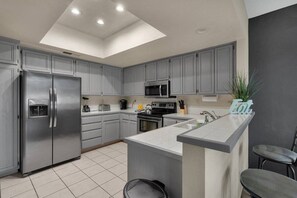 A modern kitchen with grey cabinets, stainless steel appliances, a central island, and a skylight. - Beautiful 3 Bedroom Condo with Million Dollar Views (La Quinta)