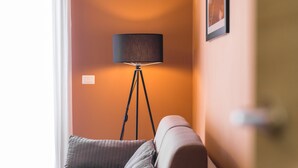 Una habitación con una lámpara de pie, un sillón acolchado y una puerta.