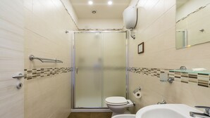 Un baño moderno con ducha envuelta en vidrio, un inodoro y un lavabo con espejo arriba.