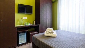 A hotel room with a bed, a desk, a television, and a wardrobe. - BH Napoli Railway - Pistacchio - 4 (Napoli)