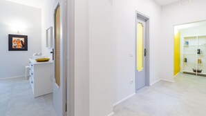 A hallway with white walls and a light-colored floor, leading to a room with a white cabinet and a framed picture on the wall. - CasaNa on Christmas Alley (Napoli)