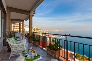 A balcony with wicker furniture, potted plants, and a view of the sea. - O-House Posillipo - Two Bedroom Apartment, Sleeps 6 (Napoli)