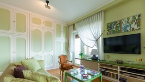 A living room with a green sofa, a glass coffee table, a television, and a bookshelf. - O-House Posillipo - Two Bedroom Apartment, Sleeps 6 (Napoli)