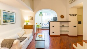 A modern living room with a sofa, coffee table, and a dining area with a table and chairs. - Parthenope's Eye on the Seafront (Napoli)