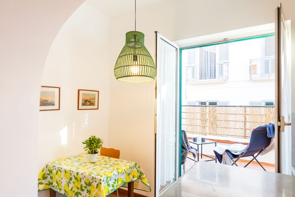 A dining area with a table, chairs, and a hanging light fixture. - Parthenope's Eye on the Seafront (Napoli)