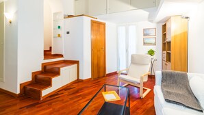 A spacious living area with a wooden staircase, a white sofa, and a glass coffee table. - Parthenope's Eye on the Seafront (Napoli)