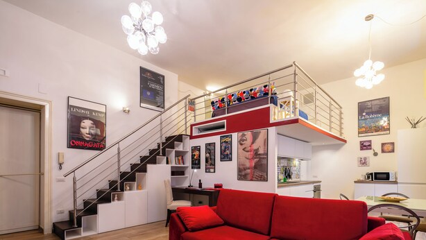 A modern living room with a red sofa, a staircase, and a dining area. - The Actors House - One Bedroom Apartment, Sleeps 4 (Napoli)