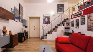 A modern living room with a red sofa, wooden coffee table, and a staircase with a railing. - The Actors House - One Bedroom Apartment, Sleeps 4 (Napoli)