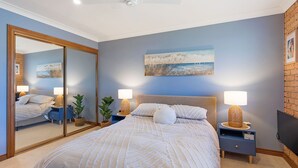 Un dormitorio con una cama grande, dos mesitas de noche con lámparas, un espejo y un cuadro en la pared.