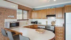 Una cocina moderna con armarios de madera, microondas integrado, lavavajillas Bosch y estufa.