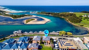 Una zona costera con un puerto deportivo, casas con techos azules y una vista despejada del océano.