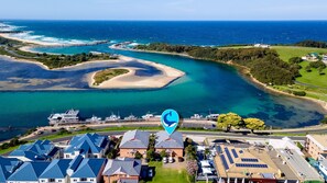 A coastal area with a marina, houses with blue roofs, and a clear view of the ocean. - Grand Pacific 2 Unit 4 -Omaroo - First Floor (Narooma)