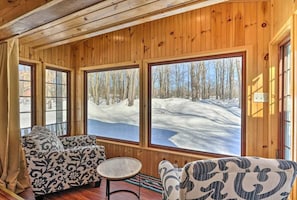Cozy cabin interior with a large window offering a view of the surrounding landscape, featuring two sofas and a small table.