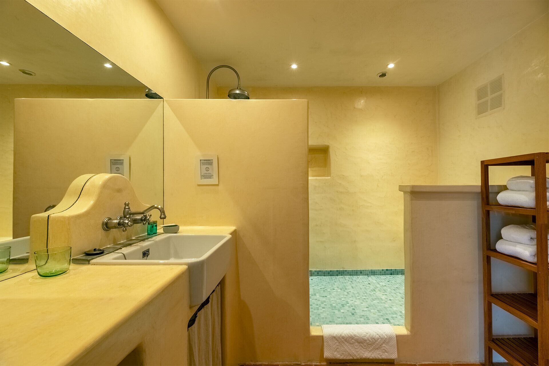 A bathroom with a sink, mirror, and shower area.