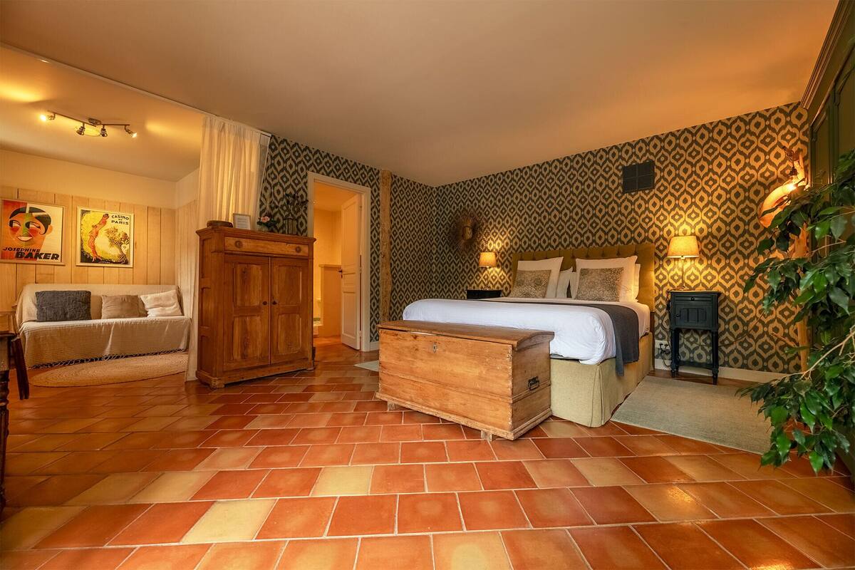 Une chambre d’hôtel avec un lit, une commode en bois, une armoire et un mur orné d’un motif.