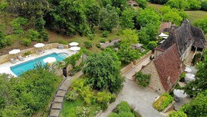 An aerial view of a property with a swimming pool, stone walls, and lush greenery. - La Tour de Cause (Saint-Cybranet)
