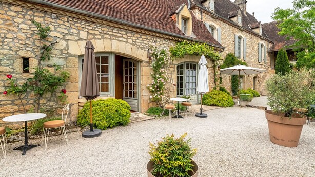 A stone building with a courtyard, featuring outdoor seating, a small garden, and a gravel path. - La Tour de Cause (Saint-Cybranet)