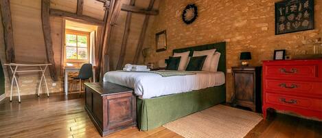 Un dormitorio rústico con una cama de madera, un escritorio y un aparador rojo.