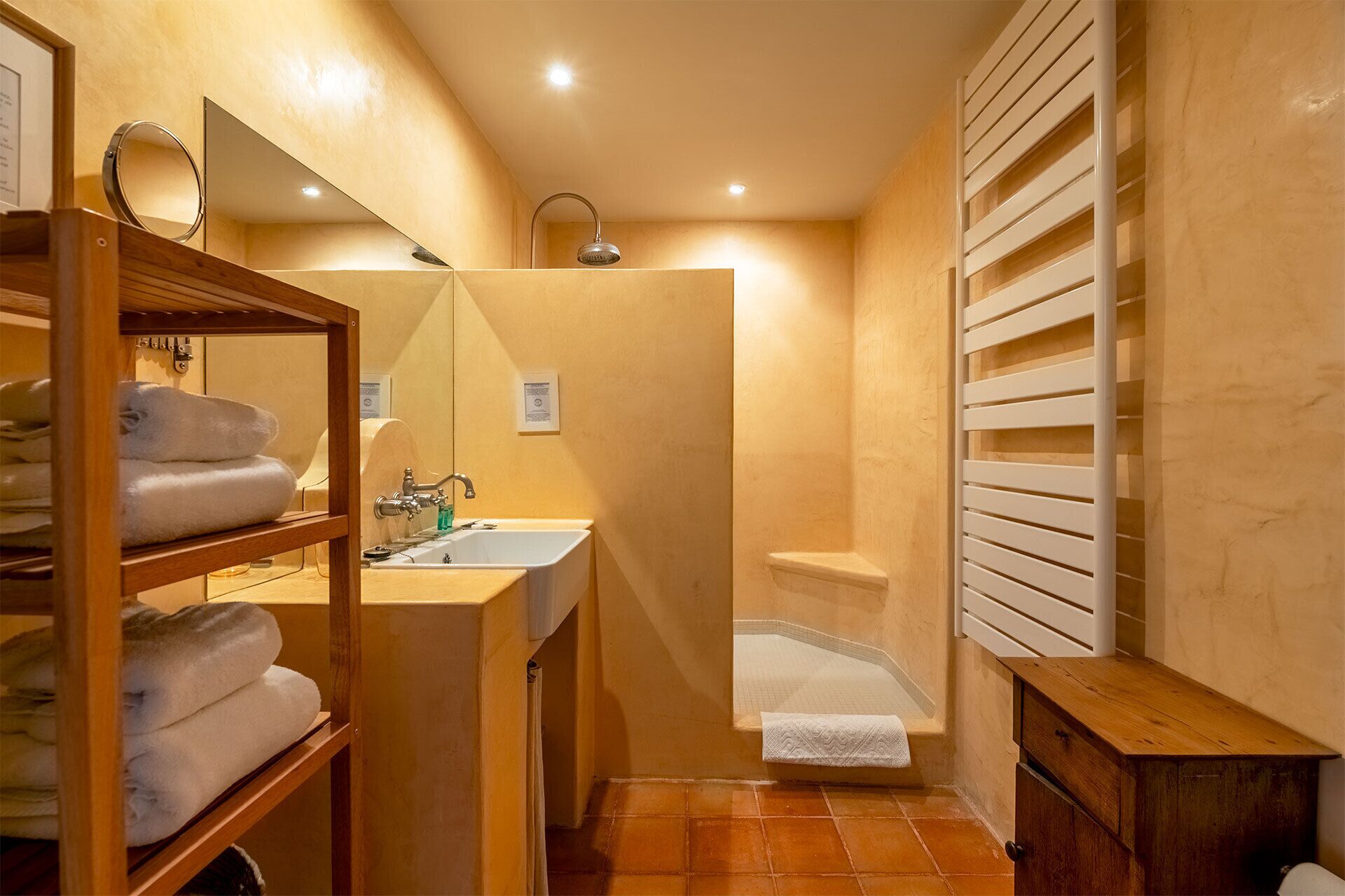 Une salle de bain équipée d’un lavabo, d’un miroir, d’un porte-serviettes et d’un espace douche.