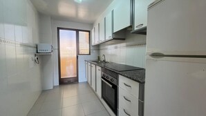A compact kitchen with white cabinets, a built-in oven, and a sink. - Tamaris playa 7ºC Solo Familias! (Xeraco Playa)