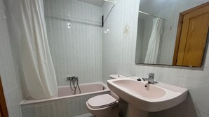 A bathroom with a bathtub, toilet, and sink. - Tamaris playa 7ºC Solo Familias! (Xeraco Playa)