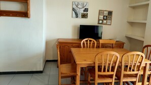A dining area with a wooden table and chairs, a television, and wall-mounted decorations.