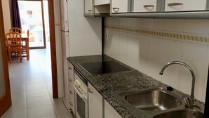 A kitchen with white cabinets, granite countertops, a stainless steel sink, and a built-in oven.