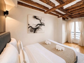 Quarto com cama, um quadro e janela com cortinas.