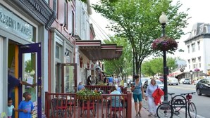 Une scène de rue avec des terrasses, des piétons et des vélos garés.