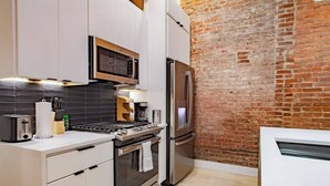 Una cucina moderna con parete in mattoni, elettrodomestici in acciaio inossidabile e piano di lavoro in legno.