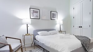 Una camera da letto con un letto, comodini, una sedia e un armadio.