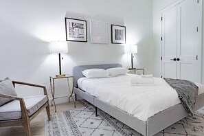 A bedroom with a bed, bedside tables, a chair, and a wardrobe.