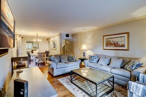 A spacious living room with a sofa set, a coffee table, and a dining area with chairs and a table.