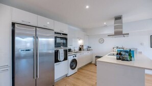 A modern kitchen with stainless steel appliances, a washing machine, and a small island with kitchen essentials. - 2 Deben Wharf, Woodbridge (Woodbridge)