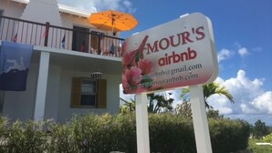 A sign for 'Amour's Airbnb' with contact information. - [A]MOUR AMOUR AMOUR

Lighthouse Views • Walk to Beaches • Classic Bermuda Charm (Hamilton)