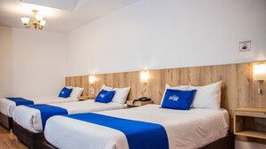 A hotel room with three beds, each with blue and white bedding, wooden headboards, and bedside lamps. - Estancia San Pedro Hotel (Cusco)